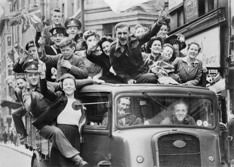 Soldiers and civilians wave flags while riding a bus at the VE Day celebrations in London on May 8 1945