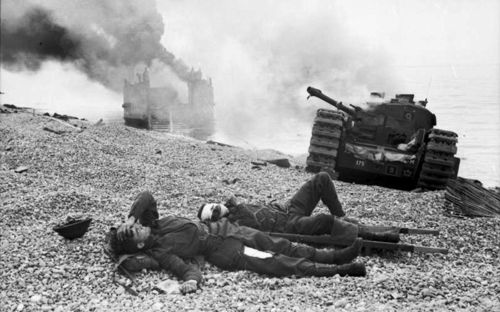 Wounded Canadian soldiers on the beach of Dieppe in front of a knocked out tank.